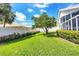 Expansive backyard featuring lush green grass, privacy wall, and a mature shade tree in a serene setting at 1330 Berkshire Ct, Venice, FL 34292