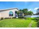 Well-maintained backyard with lush green lawn, mature tree, and beige home exterior with large windows at 1330 Berkshire Ct, Venice, FL 34292