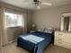 Inviting bedroom with tiled floors, fan, and a queen bed, complemented by a large window and dresser at 1401 S Mccall Rd # 106, Englewood, FL 34223