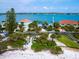 Aerial view of waterfront homes, lush landscaping, and a pristine beach offers an idyllic coastal living experience at 1604 Casey Key Rd, Nokomis, FL 34275