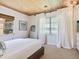 Cozy bedroom featuring a white comforter, window with sheer curtains, and wood ceiling at 1604 Casey Key Rd, Nokomis, FL 34275