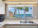Kitchen view shows stainless steel sink and a picturesque view of tropical landscaping at 1604 Casey Key Rd, Nokomis, FL 34275