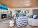 Cozy living room features a brick fireplace, wood ceiling, comfortable seating, and a large window with palm tree views at 1604 Casey Key Rd, Nokomis, FL 34275