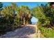 A sandy path with wooden posts and rope fences leads through lush greenery to the beach at 1871 Bridge St, Englewood, FL 34223