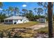 Aerial view of a white house with large yard and separate garage, surrounded by tall trees at 1871 Bridge St, Englewood, FL 34223