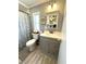 Well-lit bathroom with a vanity, storage cabinet, and a shower with a patterned curtain at 199 Palm Harbor Dr, North Port, FL 34287