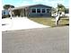 Charming gray home with a carport, manicured lawn, and lush palm trees at 199 Palm Harbor Dr, North Port, FL 34287