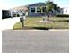 Quaint gray home with a mailbox, complemented by vibrant green lawn and palm trees at 199 Palm Harbor Dr, North Port, FL 34287
