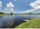 Peaceful lake view of residences across the water with a small boat dock in the foreground at 199 Palm Harbor Dr, North Port, FL 34287