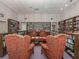 Community library featuring bookshelves filled with books, comfortable chairs and tables for residents to use at 199 Palm Harbor Dr, North Port, FL 34287
