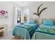 A well-lit bedroom featuring matching twin beds, with cozy blue quilts and two sunny windows at 20390 Cavallo Ct, Venice, FL 34292