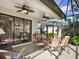 A covered outdoor lanai offering seating, ceiling fans, and views of the landscaped backyard at 20390 Cavallo Ct, Venice, FL 34292
