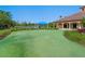 A putting green is surrounded by manicured landscaping, a lake view, and a blue tent at 2059 Batello Dr, Venice, FL 34292