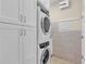 The laundry room has modern stacked washer and dryer units and ample cabinet storage space at 2172 Chenille Ct, Venice, FL 34292