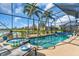 Screened-in pool and spa with a serene lake view and tropical landscaping in the backyard at 2172 Chenille Ct, Venice, FL 34292