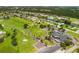 An aerial view captures a community with a golf course, pool, and tennis courts at 221 Mark Twain Ln, Rotonda West, FL 33947