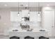 Beautiful white kitchen with quartz countertops, stainless appliances, and island with seating beneath modern pendant lights at 228 Caserta Ct, North Venice, FL 34275