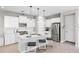 Well-lit white kitchen features an island with seating, stainless steel appliances, and modern pendant lighting at 228 Caserta Ct, North Venice, FL 34275