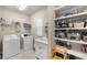 Functional laundry room with washer, dryer, sink, storage shelves and a bright, clean aesthetic at 228 Caserta Ct, North Venice, FL 34275