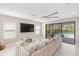 Living room with sectional couch, white tile flooring, large tv, and view to the outdoor pool area through glass doors at 228 Caserta Ct, North Venice, FL 34275
