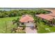 Front aerial shot of the property featuring a tile roof, solar panels, and well-manicured lawn at 24036 Spartina Dr, Venice, FL 34293