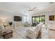 Bright living room with a large window view, featuring comfortable seating, a TV, and neutral color palette at 24036 Spartina Dr, Venice, FL 34293