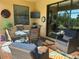 Comfortable covered patio featuring a dining table set, comfortable seating, outdoor TV, and sliding glass doors at 24036 Spartina Dr, Venice, FL 34293