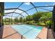 Enclosed pool area featuring a pool, spa, brick deck, and views of the surrounding greenery at 24036 Spartina Dr, Venice, FL 34293