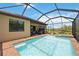 Enclosed pool area featuring a pool, spa, brick deck, and views of the surrounding backyard at 24036 Spartina Dr, Venice, FL 34293