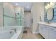 Bright bathroom boasts double vanity, soaking tub with shower, and white wood-look tile flooring at 29260 Coral Harbour Dr, Englewood, FL 34223