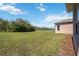 A spacious, grassy backyard has a pond on the property line and a wood-chipped walkway along the side of the home at 312 Londonderry Dr, Sarasota, FL 34240