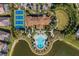 Overhead view of the clubhouse with its pool, tennis courts, lush landscaping, and nearby lake at 448 Bocelli Dr, Nokomis, FL 34275