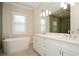 Modern bathroom featuring dual sinks, marble countertop, a soaking tub, and luxury finishes at 448 Bocelli Dr, Nokomis, FL 34275