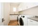 Laundry room featuring white cabinets, a gray countertop and modern washer and dryer units at 448 Bocelli Dr, Nokomis, FL 34275