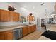 Well-lit kitchen featuring tile flooring, wooden cabinets, and stainless steel dishwasher at 5458 Jessamine Ave, North Port, FL 34291