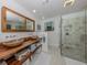 Bathroom with double sinks, wooden countertop, decorative mirrors, and walk-in glass shower at 601 Apalachicola Rd, Venice, FL 34285