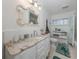 Bathroom with marble countertops, white cabinets, decorative mirror, and shower at 601 Apalachicola Rd, Venice, FL 34285