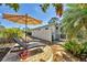 Backyard patio featuring lounge chairs, shade umbrella, and tropical foliage at 6216 Pecan Rd, Venice, FL 34293