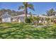 Well-maintained front yard featuring lush green grass, tropical landscaping, and a charming white picket fence at 6216 Pecan Rd, Venice, FL 34293