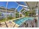 Beautiful pool with a screened enclosure, surrounded by greenery and brick pavers at 6216 Pecan Rd, Venice, FL 34293