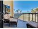 Balcony seating area overlooking a beach with ocean views, palm trees, and clear skies at 700 Golden Beach Blvd # 224, Venice, FL 34285