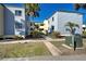 Exterior of condo building with light blue siding, landscaping, and sidewalk at 700 Golden Beach Blvd # 224, Venice, FL 34285