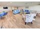 Large community room with blue couches, chairs, tables, and wood-look flooring at 700 Golden Beach Blvd # 224, Venice, FL 34285