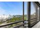 Balcony view from a condo overlooking lush greenery, open water, and a distant cityscape under a blue sky at 770 S Palm Ave # 404, Sarasota, FL 34236
