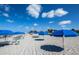 Inviting beach scene with blue umbrellas, lounge chairs, and clear skies, offering a perfect vacation spot at 8170 Casa De Meadows Dr, Englewood, FL 34224