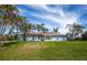 Charming light blue home featuring a lush lawn and tropical landscaping with palm trees against a blue sky at 8170 Casa De Meadows Dr, Englewood, FL 34224