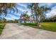 Charming single-story home with lush tropical landscaping and a long driveway leading to the front entrance at 8170 Casa De Meadows Dr, Englewood, FL 34224