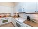 Well-lit kitchen featuring white cabinets, granite countertops, and modern appliances at 8170 Casa De Meadows Dr, Englewood, FL 34224