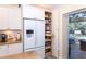 Kitchen pantry with pull-out shelves, stainless steel refrigerator and water dispenser at 8170 Casa De Meadows Dr, Englewood, FL 34224