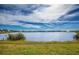 Scenic view of pond featuring a lush grassy shoreline under a beautiful, expansive sky at 8170 Casa De Meadows Dr, Englewood, FL 34224